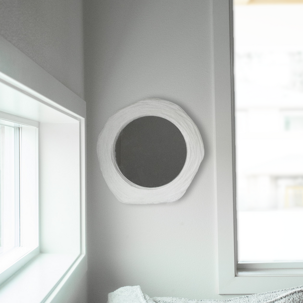 Round gray acoustic panel on a white wall with windows